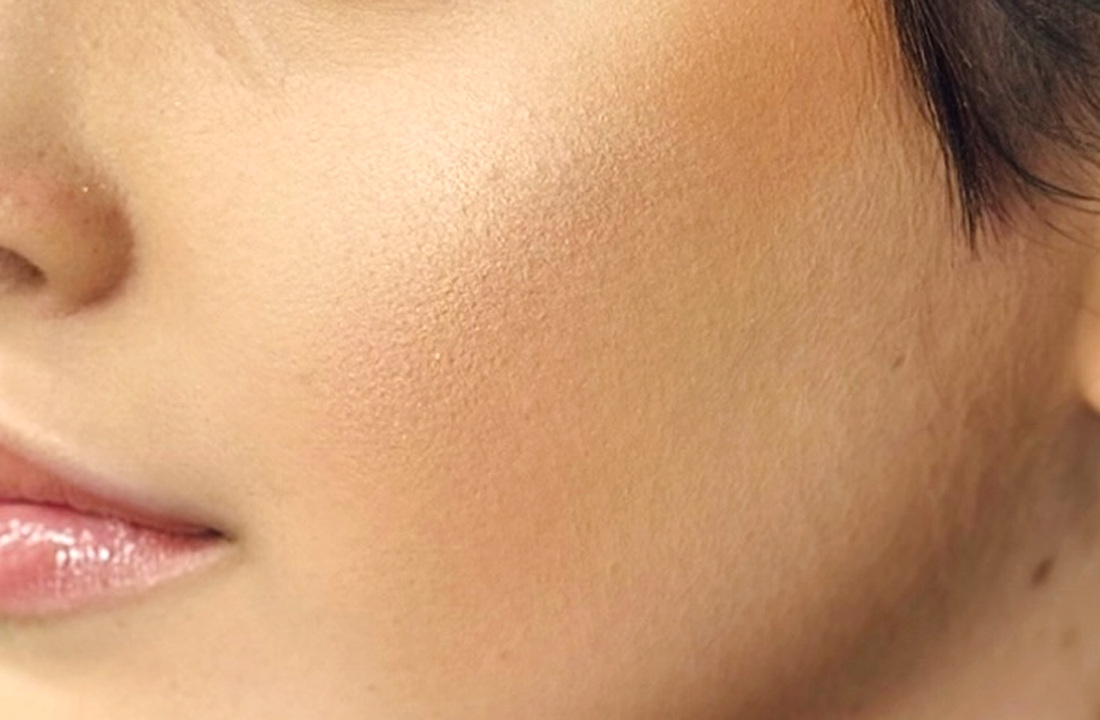 Primer plano de piel luminosa con acabado satinado y maquillaje natural